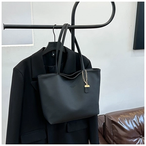 Detailed view of the black lychee grain leather tote bag with gold chain and logo