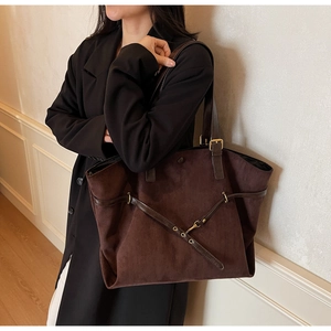 Detail of dark brown matte suede tote bag featuring metallic grommets and hook accents