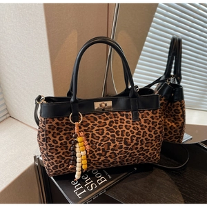 Dettaglio della borsa tote scamosciata leopardata con manici in pelle nera e ciondolo