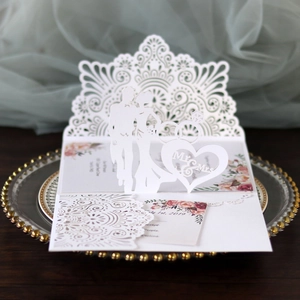 Macro detail of laser-cut wedding invitation featuring 3D Mr & Mrs silhouette and flowers