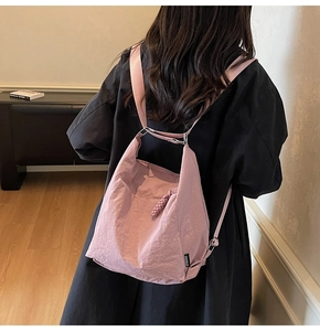 Detail of light pink wrinkled nylon backpack with adjustable straps on a female model