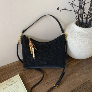 Detail of vintage black bucket bag with textured leather and colorful wooden bead charm
