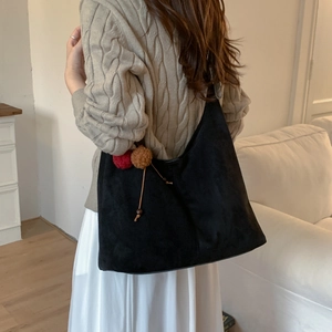 Détail du sac hobo en daim givré noir avec décoration de pompon en fausse fourrure colorée