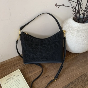Detailed macro of vintage black leather shoulder bag with gold hardware and logo plate