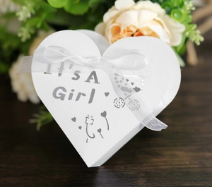 Detail of white laser-cut 'It's a Girl' heart candy box with ribbons for baby showers