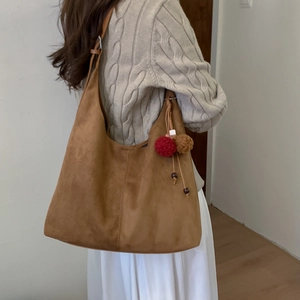 Sac hobo marron givré avec breloques porté par un mannequin dans un style décontracté