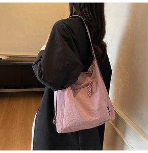 Close-up of pink nylon shoulder bag featuring braided side detailing and water-resistant fabric