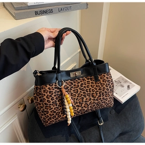 Dettaglio della borsa tote leopardata con finiture in pelle nera e ciondolo di perline