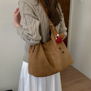 Sac fourre-tout en daim marron avec breloque porté par un mannequin en style automne