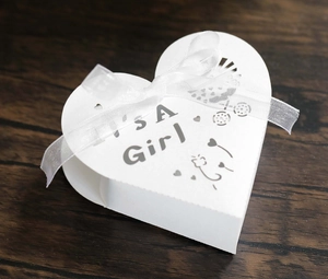 Detail of white heart-shaped favor box with It's a Girl laser cut text and ribbon bow