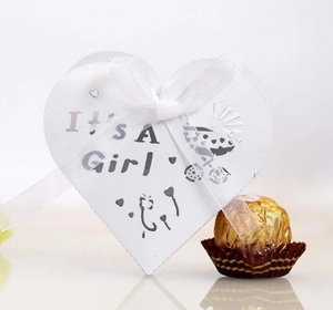 Detail of white heart-shaped gift box with It's A Girl print and white silk ribbon