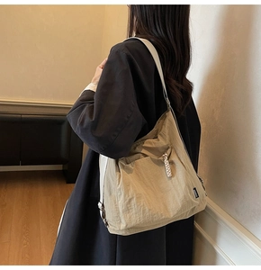 Detail view of khaki nylon tote bag with hidden zipper pocket and side branding label