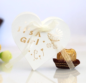 Detail of white heart favor box with gold It's a Girl text and a white silk ribbon
