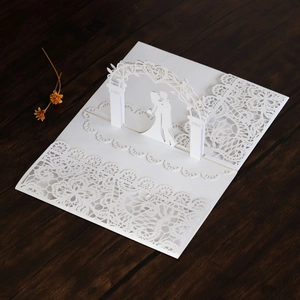Detail of laser-cut lace 3D wedding card showing a bride and groom under a white archway