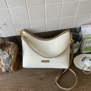 Detail of off-white bucket bag with vintage crackle texture and gold metal logo