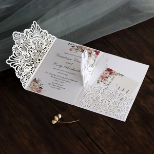 Nahaufnahme der lasergeschnittenen Hochzeitseinladung mit Blumendesign auf dunklem Holz