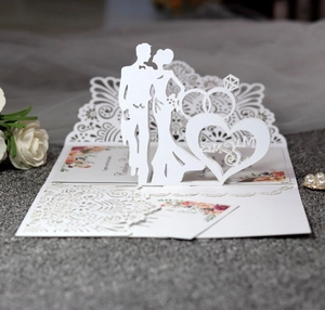 Macro shot of 3D laser-cut wedding invitation featuring a couple silhouette and rings