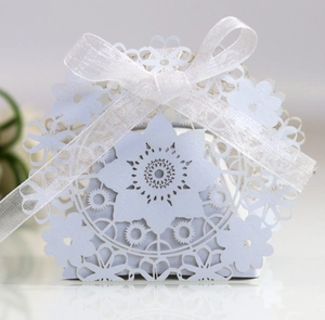 Detail of white laser-cut hollow pattern on wedding favor box with ribbon bow
