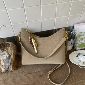 Detail view of beige retro bucket bag featuring colorful wooden beads and gold buckles