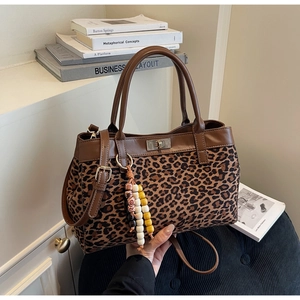 Dettaglio borsa leopardata con rifiniture in pelle marrone e ciondolo a nappa con perline