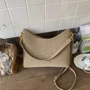 Macro detail of khaki crescent bag with pebble leather texture and gold hardware