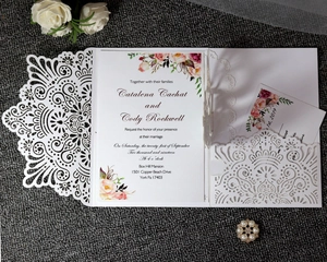 Detail of laser-cut wedding invitation with elegant floral lining and ivory lace pattern