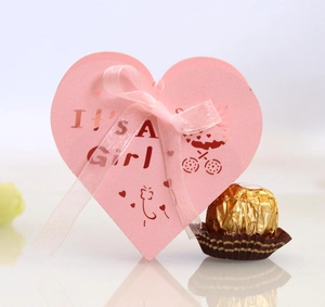 Pink heart-shaped favor box with It's A Girl tag and ribbon for baby shower candy