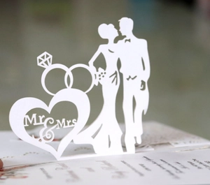 Detail of white laser-cut wedding card featuring Mr & Mrs silhouettes and diamond rings