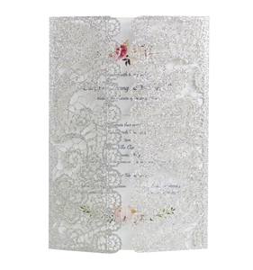 Macro shot of silver glitter lace laser-cut wedding invitation with elegant floral detail