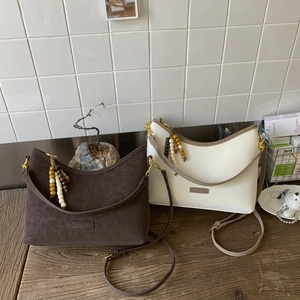 Detail of vintage bucket bags in coffee suede and off-white leather with wooden bead charm