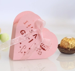 Pink heart-shaped favor box with It's a Girl text and baby carriage hollow patterns