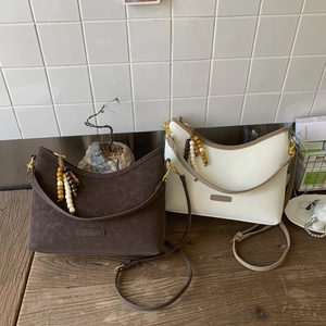 Detail of vintage bucket bags in brown and beige with boho bead charms and dual straps