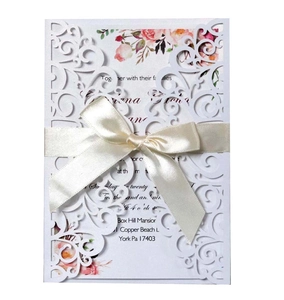 Detailed laser cut lace wedding invitation with floral insert and cream silk ribbon bow