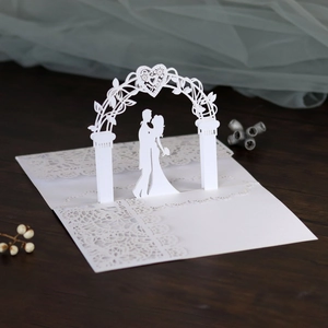 Detailed laser-cut lace wedding card with silhouette of bride and groom under a heart arch