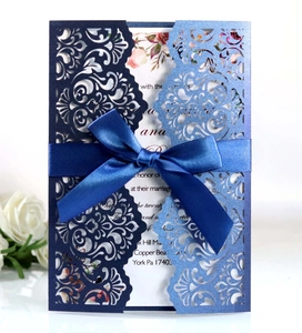 Laser cut wedding invitation with navy blue bow and floral pattern on pearl paper