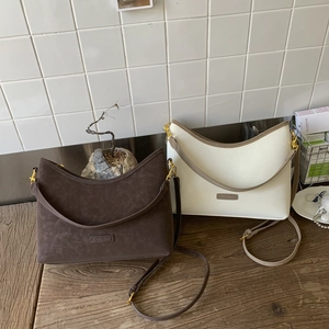 Detail view of retro bucket bags in dark brown and beige with golden metal hardware