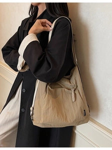 Large khaki tote bag with textured pleats and woven zipper pull shown on model shoulder