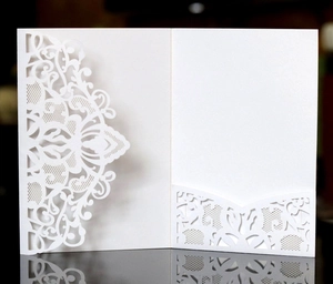 Détail du faire-part blanc découpé au laser avec motif floral délicat et pochette interne