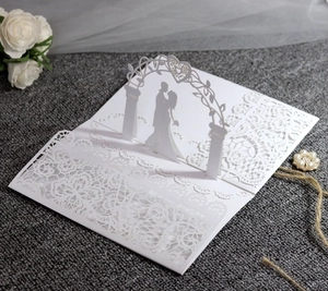 Detail showing 3D laser-cut lace wedding card with silhouette of couple under heart arch