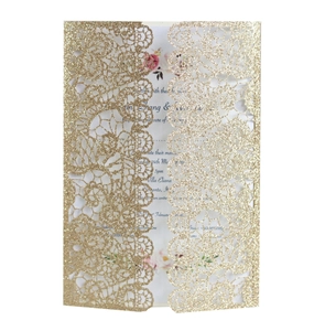 Detail of laser-cut gold glitter wedding invitation with elegant lace pattern and floral insert