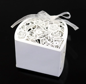 Detailweergave van een lasergesneden witte snoepdoos met delicate roospatronen en lint.