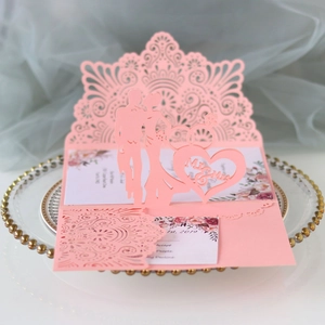 Detail of pink laser-cut wedding invitation featuring Mr & Mrs silhouettes on a porcelain plate