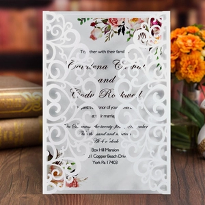 Detailed laser-cut pattern on elegant white wedding invitation with floral insert
