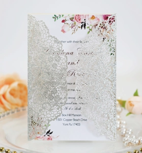 Detail of silver glitter laser cut lace wedding invitation with floral printed inner card