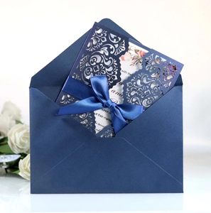 Macro view of laser cut wedding invitation with blue ribbon and floral inner card