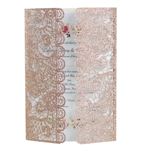 Close-up of laser-cut rose gold glitter lace wedding invitation with floral insert