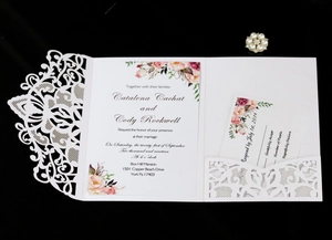 Détail du faire-part de mariage ajouré au laser avec carte florale et RSVP sur fond noir