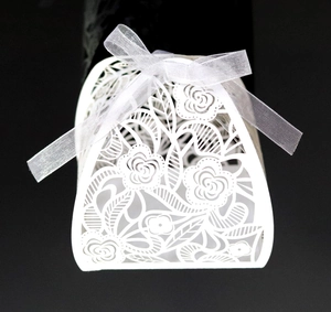 Detail van een lasergesneden bloemenhuwelijksbedankje met een witte satijnen strik