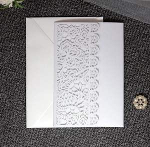 Detailed laser-cut lace wedding invitation card with white envelope on grey background