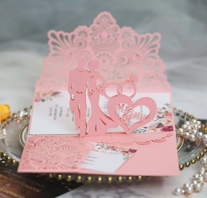 Detail of pink laser-cut wedding invitation featuring pop-up Mr & Mrs design and pearls